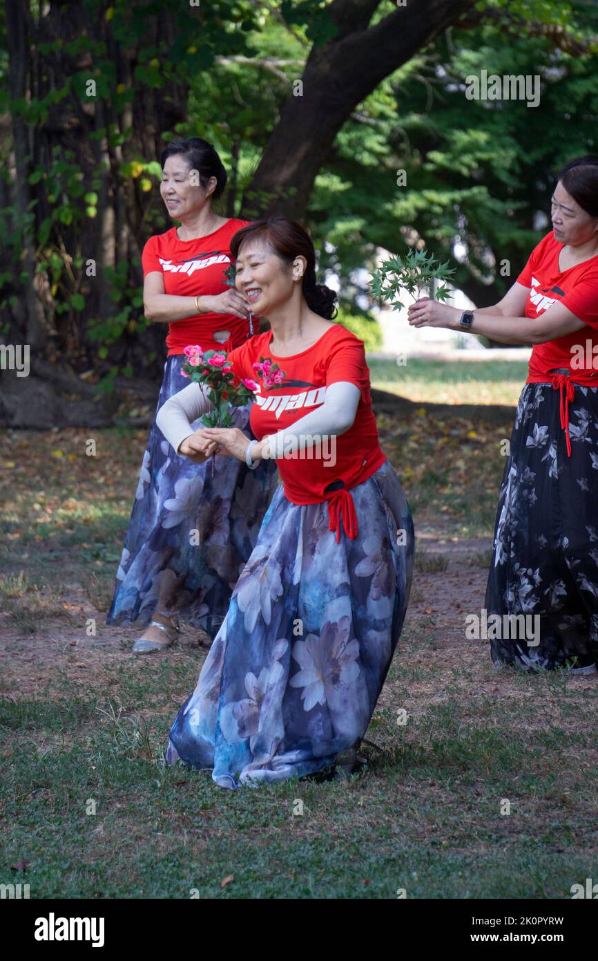 Part of a large group of Chinese American women at a yuanji dance & exercise class in a park in Queens, NYC. It's a Chinese morning tradition. Stock Photo
