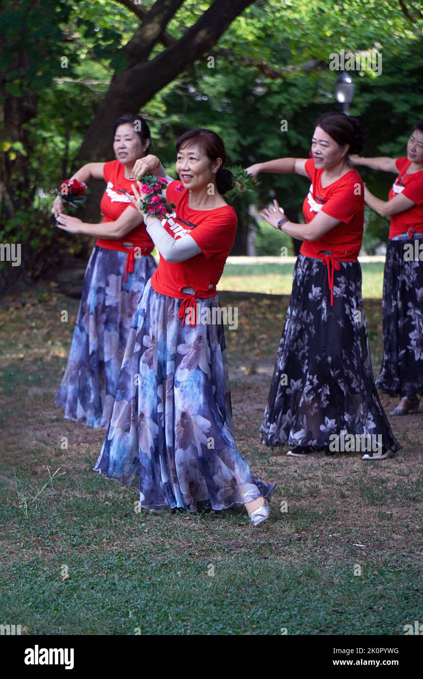 Part of a large group of Chinese American women at a yuanji dance & exercise class in a park in Queens, NYC. It's a Chinese morning tradition. Stock Photo