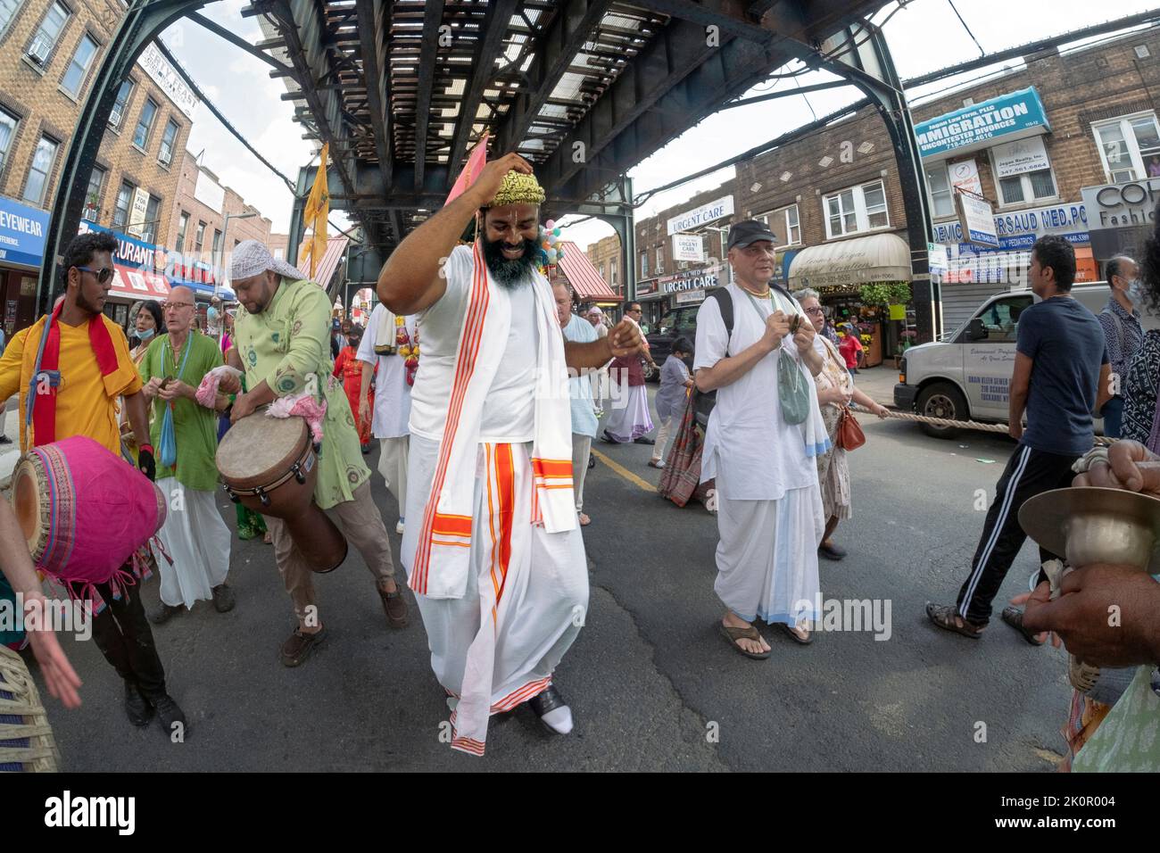 Ecstatic Hare Krishna Hindus dance & play music under the elevated subway at the annual Ratha Yatra parade in Richmond Hill, Queens, New York. Stock Photo