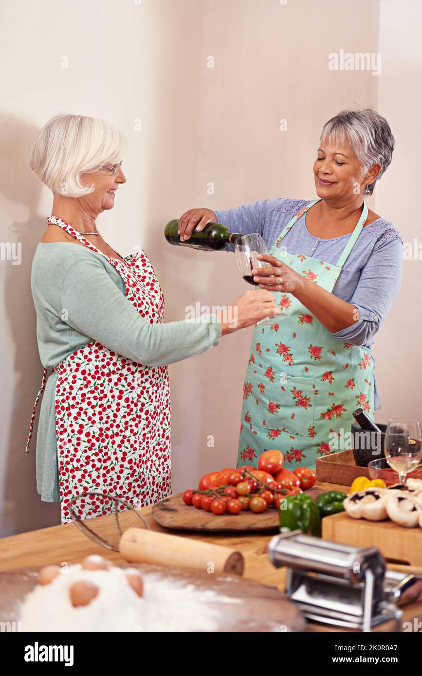 Home cooked fun with a dash of wine. two senior woman drinking wine