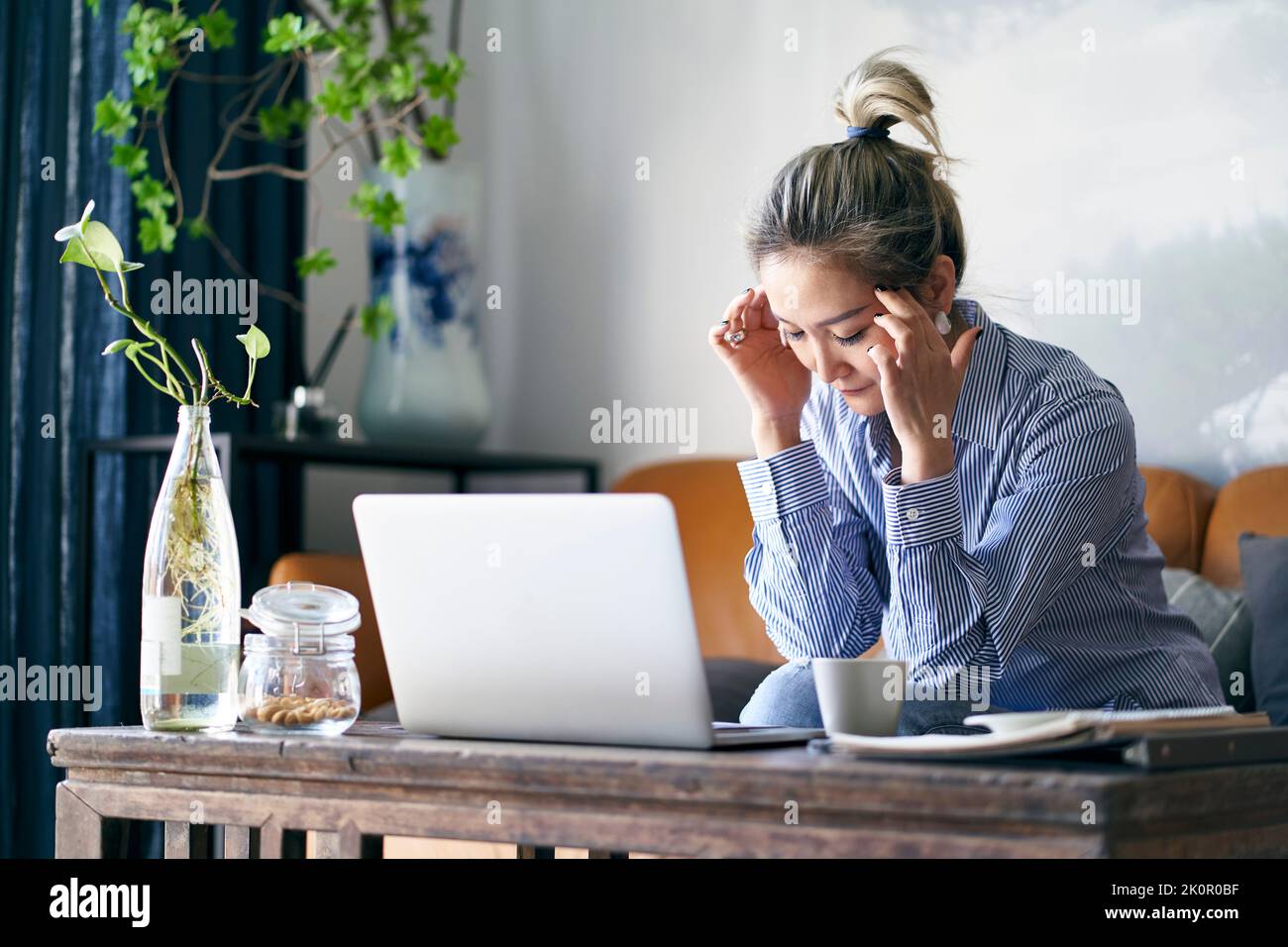 mature professional asian business woman working from home appearing to be tired and exhausted Stock Photo
