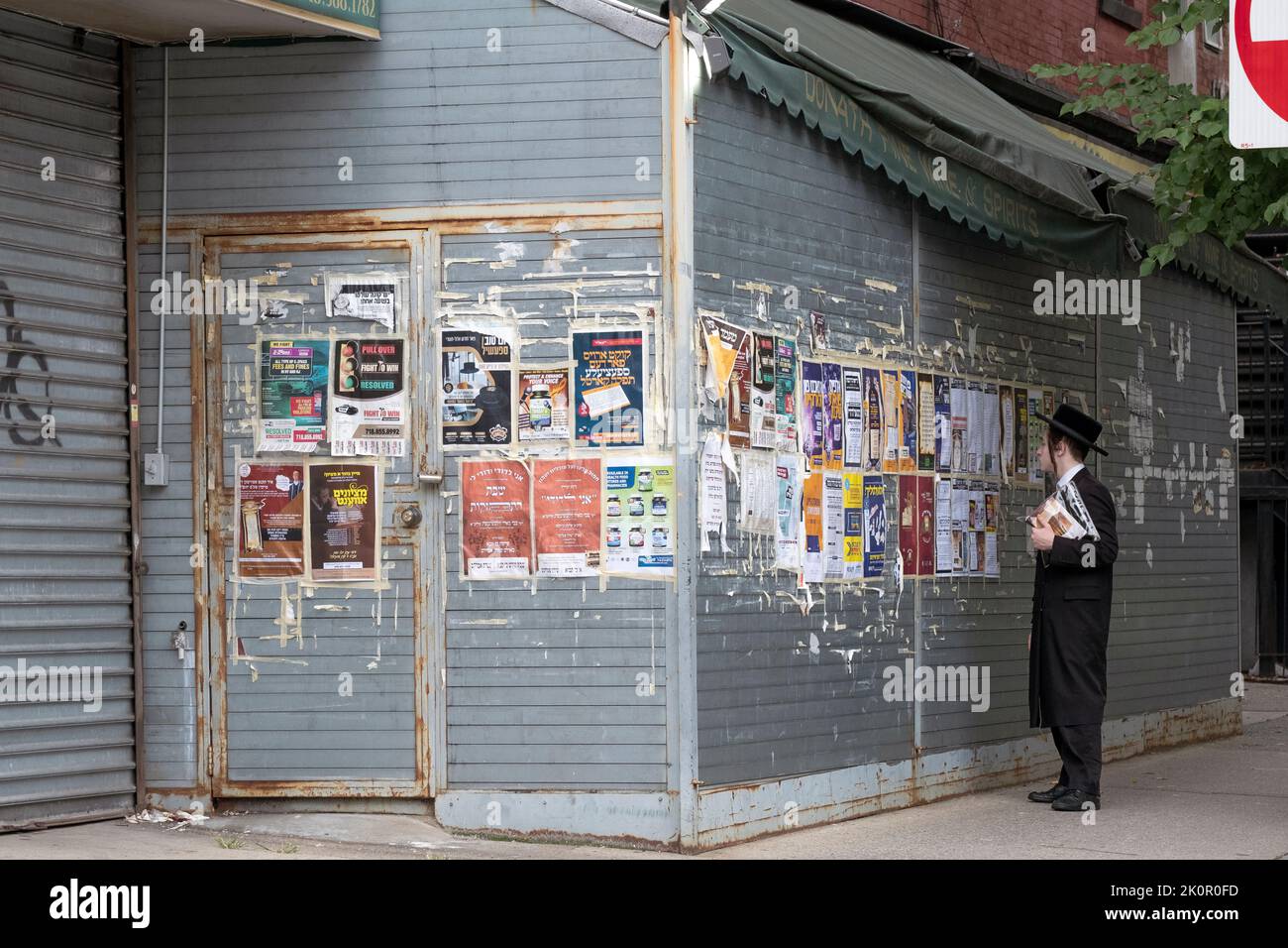 A Hasidic Jewish young man read signs just off Lee Avenue in Williamsburg that are in Yiddish, Hebrew and English. Stock Photo