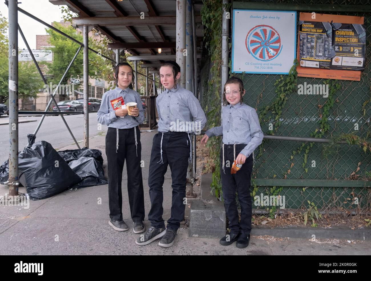 3 orthodox Jewish brothers wait for their school bus on Lee Avenue in Williamsburg, Brooklyn, New York City. Stock Photo
