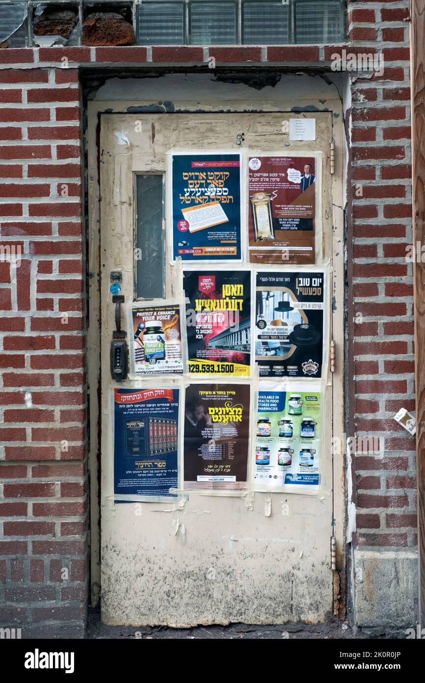 A doorway in an orthodox Jewish neighborhood with advertisements in english, Yiddish & Hebrew. On Lee Avenue in Williamsburg, Brooklyn, New York City. Stock Photo