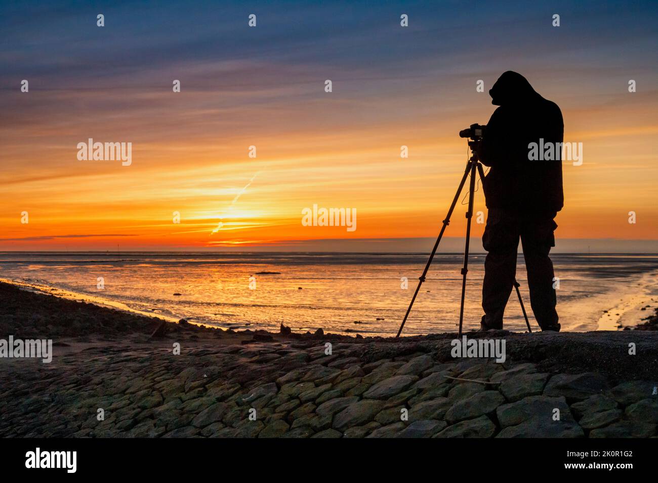 Tourist with camera during sunset on Trischedamm, North Sea at low tide Stock Photo