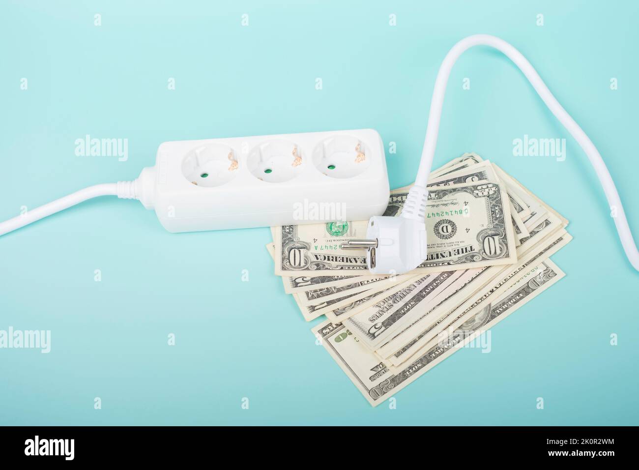 Electric power strip extension cord and US dollar bill banknotes on light blue background