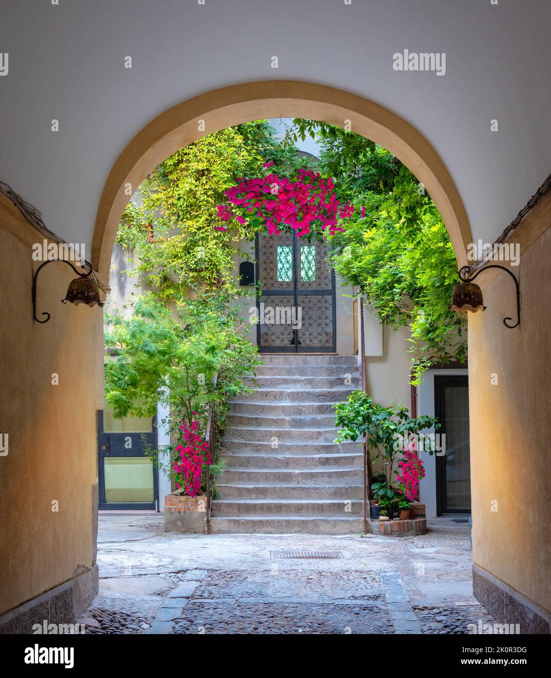 View of a house with arched medieval architecture with stairs and flowers in the window in Tuscani, Italy Stock Photo