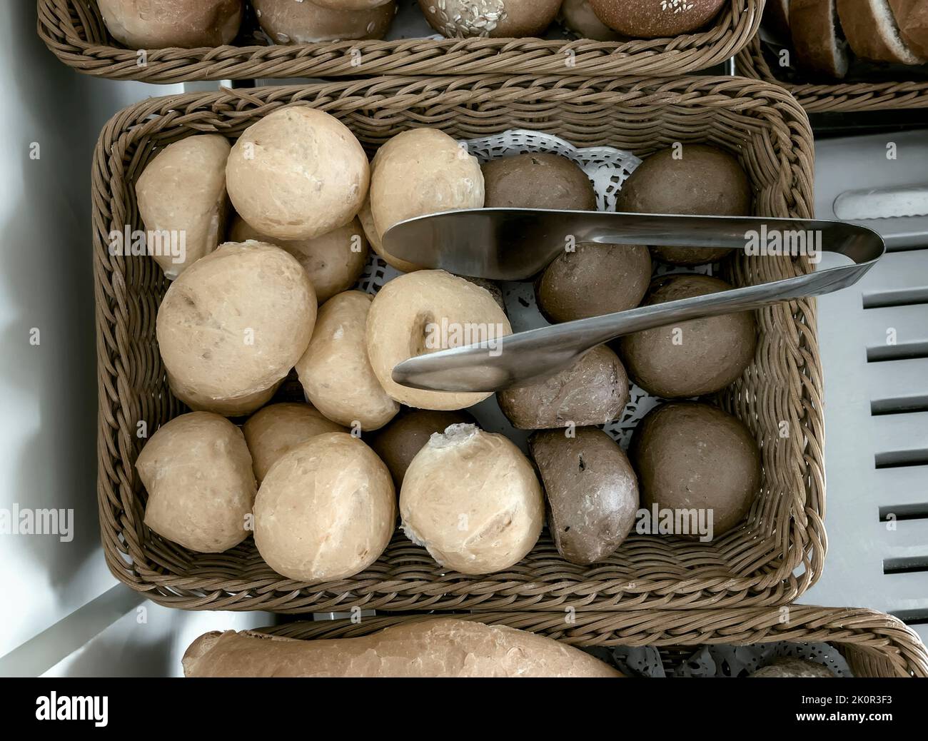 Delicious buns are on the table in a wicker basket. Top view, close-up. Stock Photo