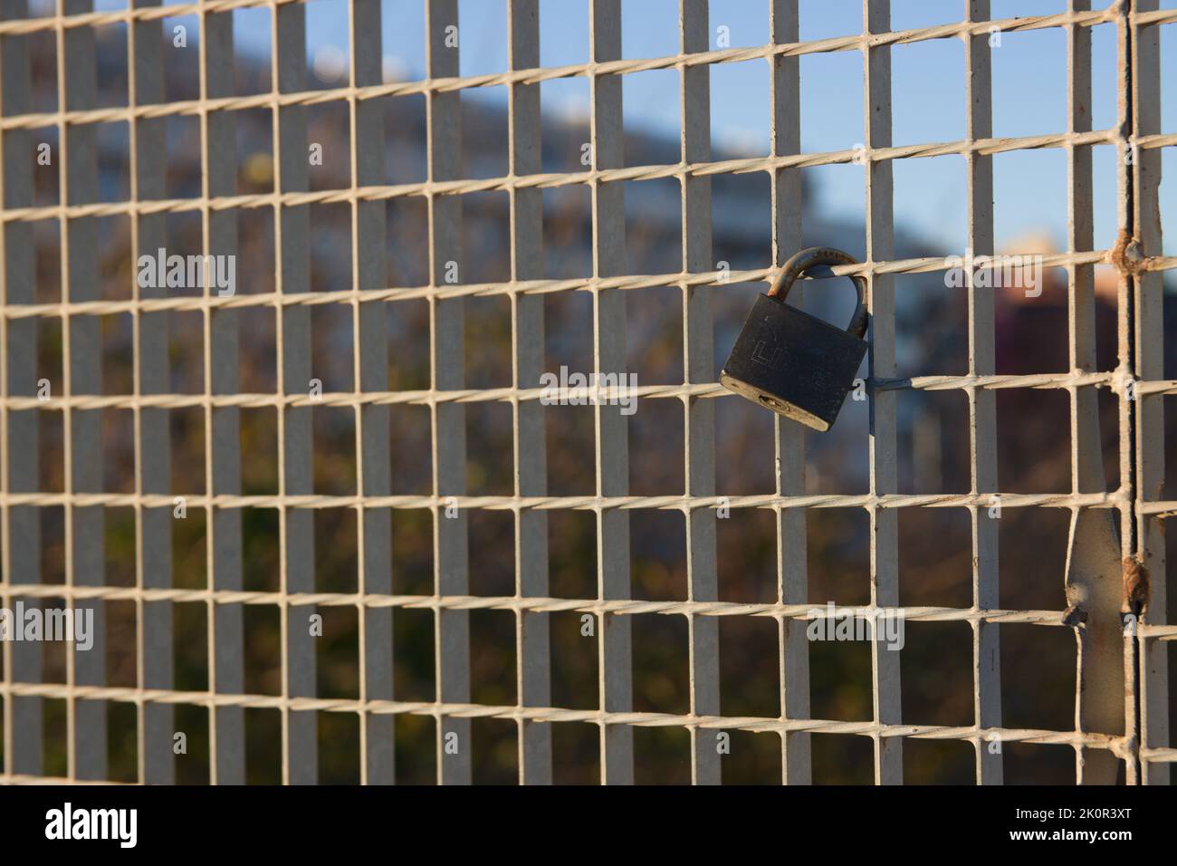 Detail of a padlock that is on a bridge fence during a sunset. Image with copy space Stock Photo