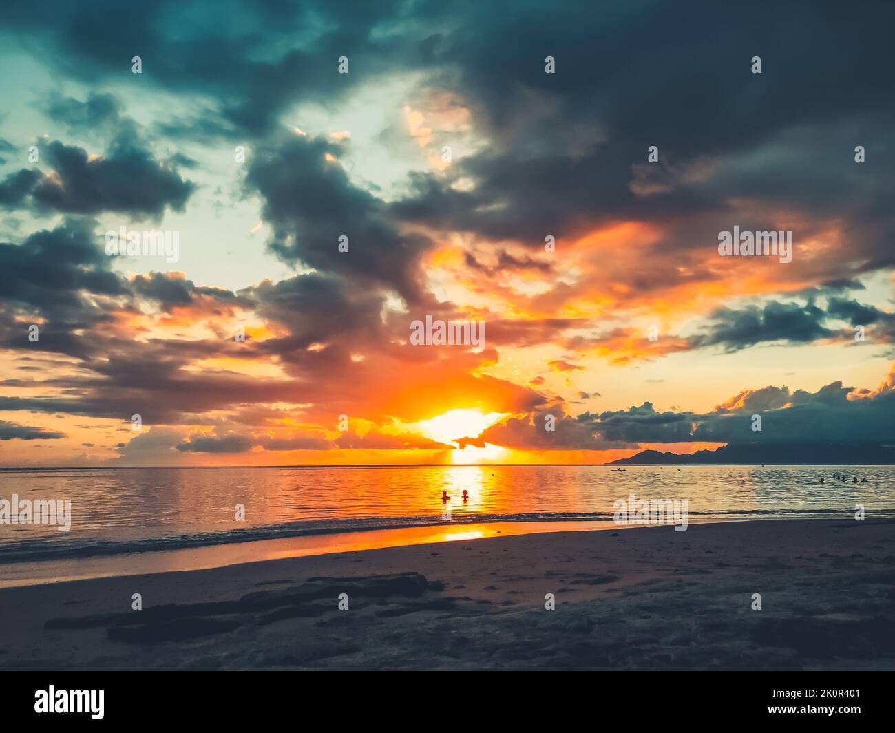Multi color bright sunset over sea sand beach. People relax and watch sun down landscape. Blue and orange clouds sky. Wonderful nature landscape during sunset. Travel, tourism, adventure concept image Stock Photo