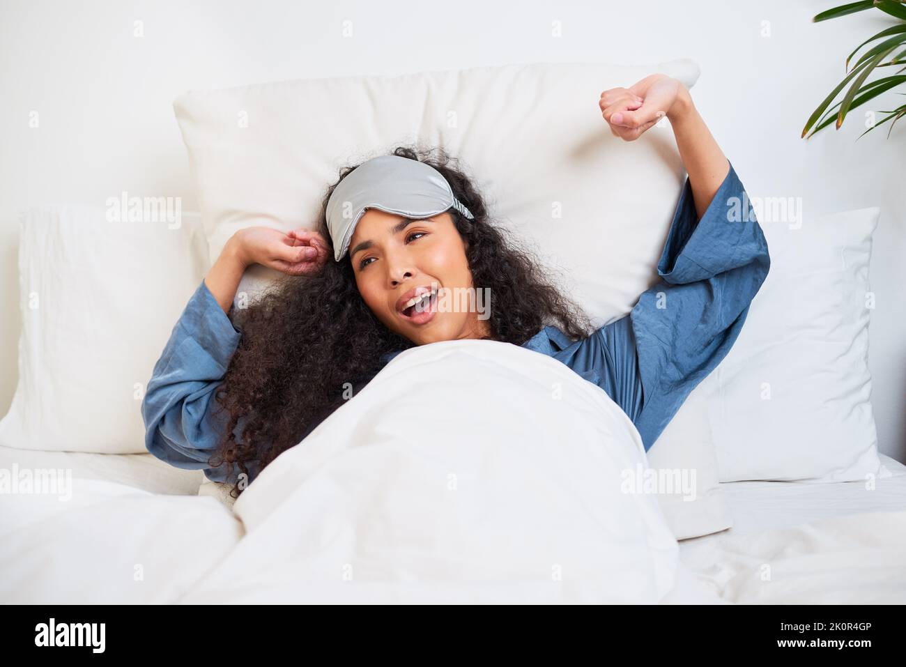 A young multiethnic woman stretches and yawns waking up with sleep