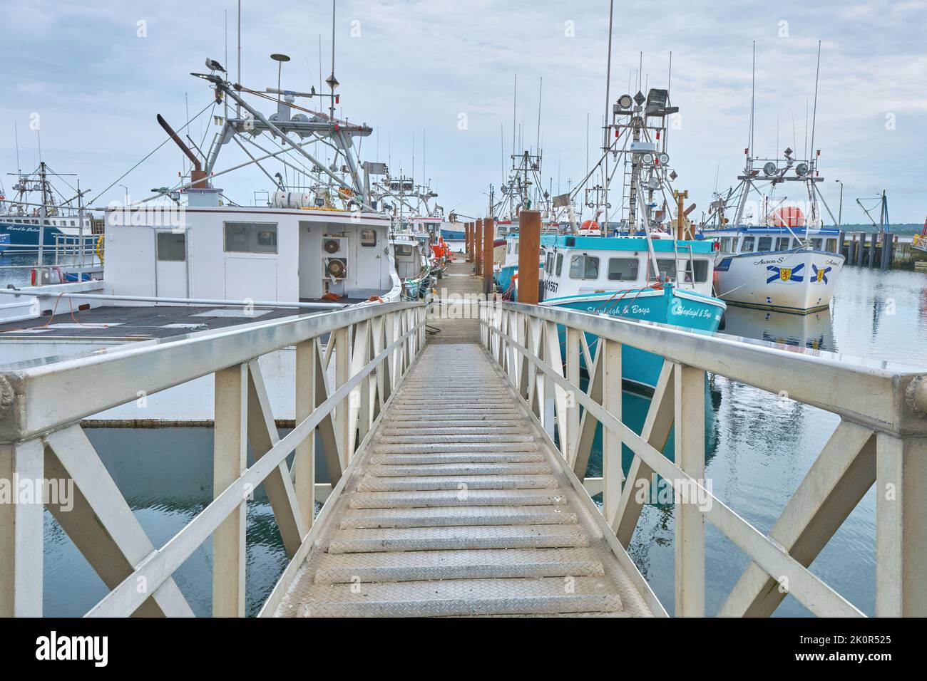 Ramp leading down to the dock at Meteghan Nova Scotia where numerous fishing boats are moored. Stock Photo