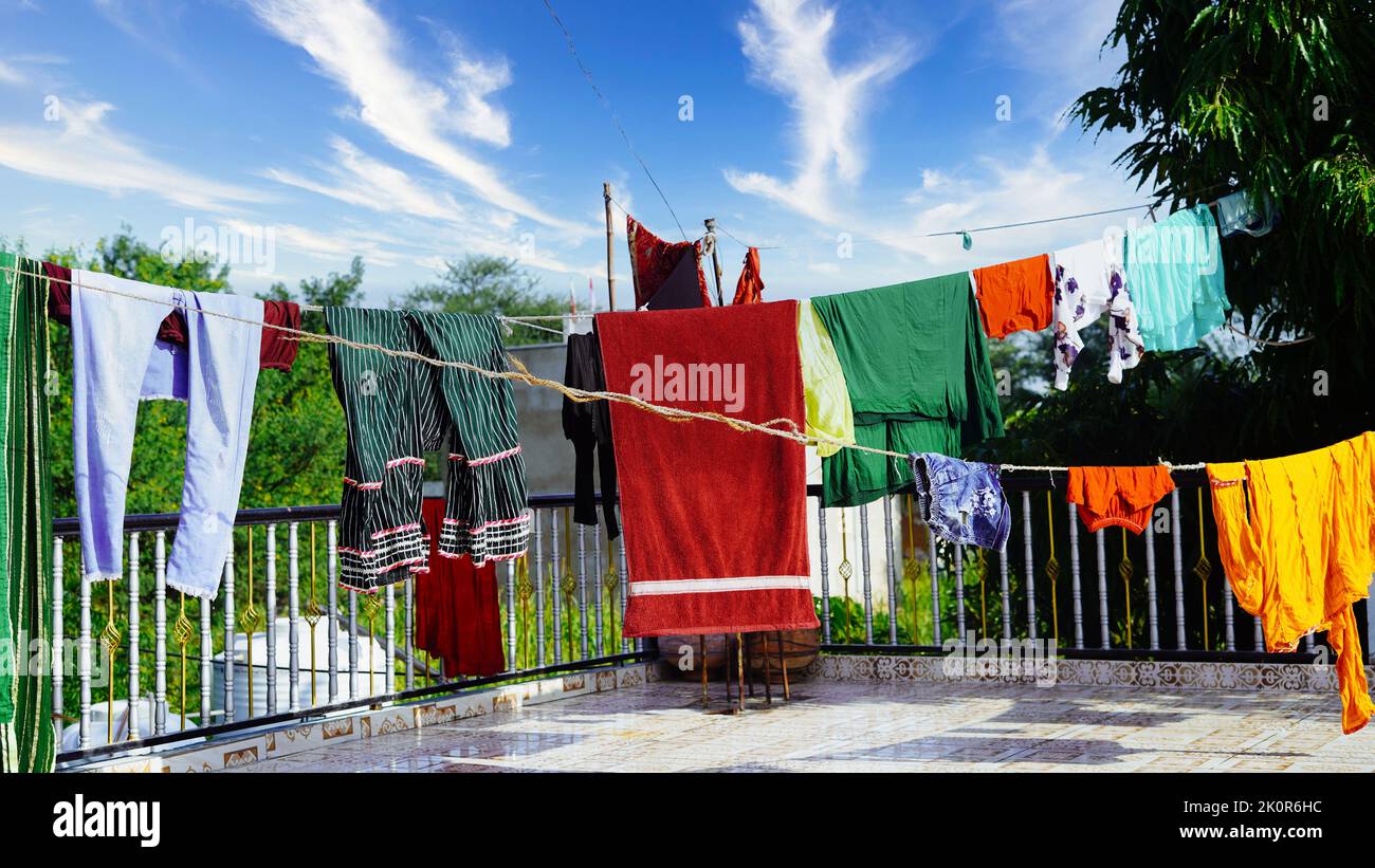Laundry line with clothes on green tree background. Laundry drying on the roof. Stock Photo