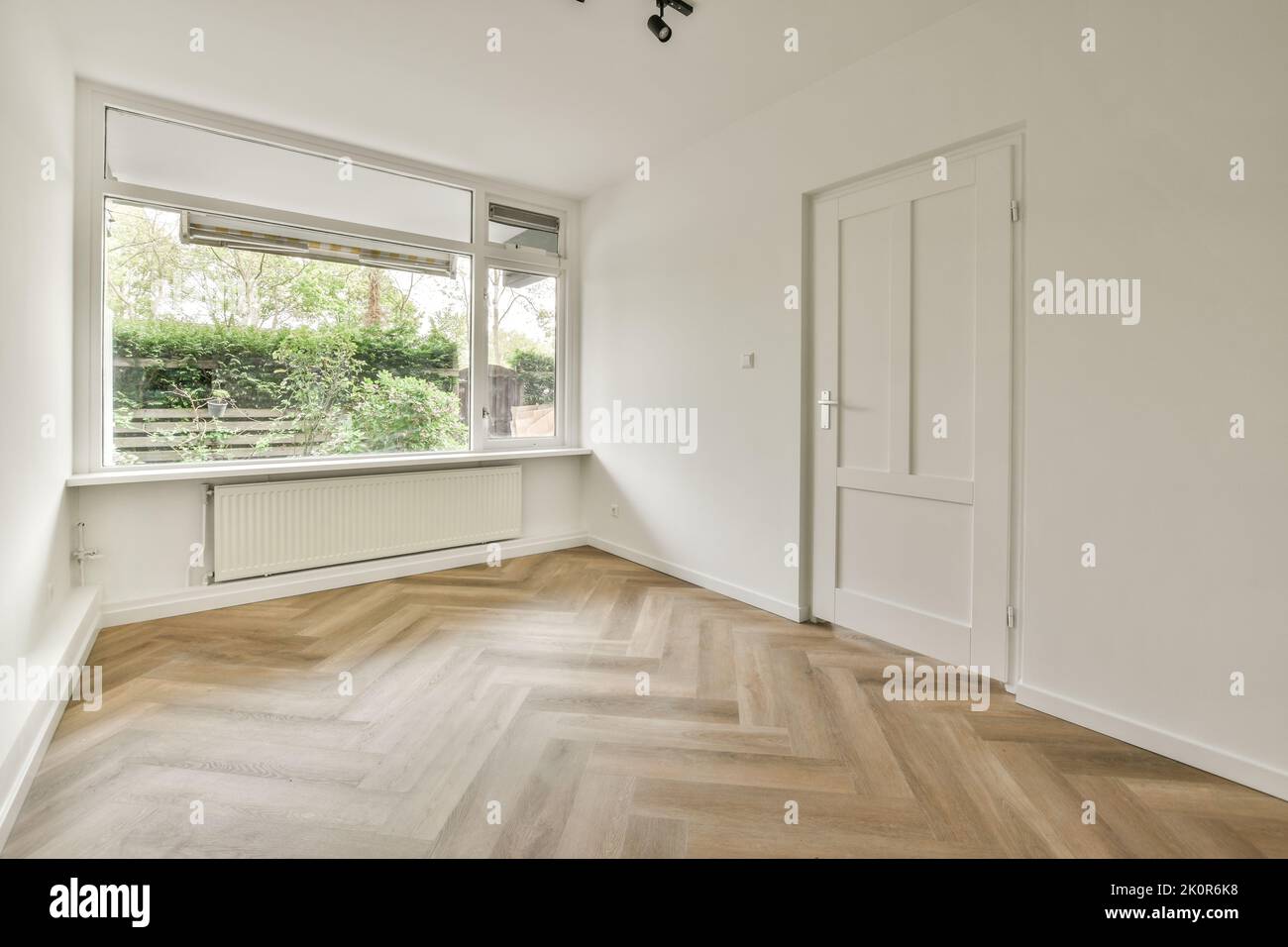 Plastic window and radiator on white wall in empty light room at home ...