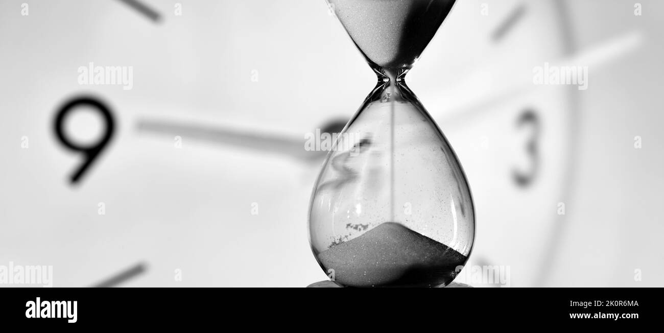 Reloj de arena y reloj redondo midiendo el tiempo en blanco y negro Stock Photo