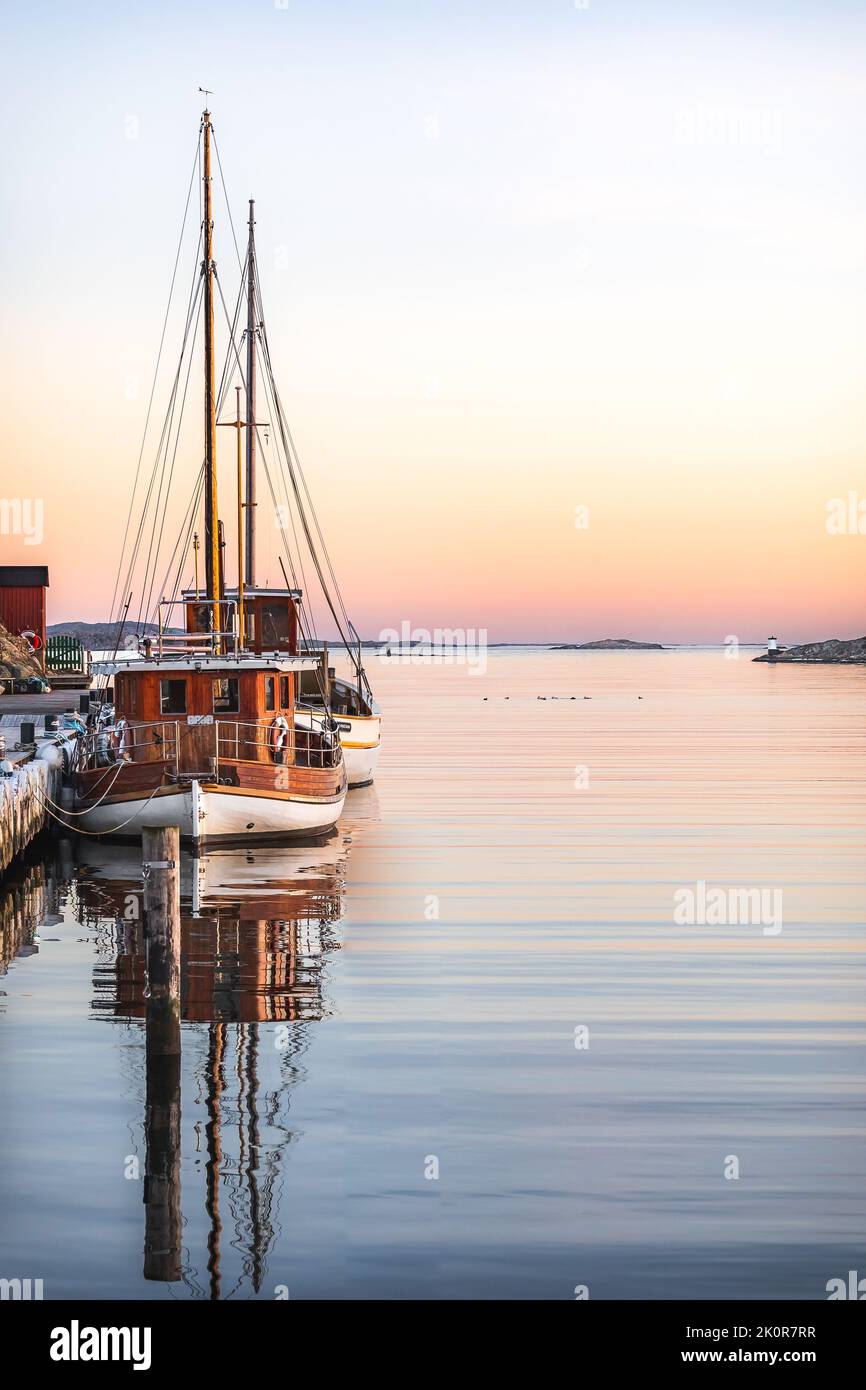 The vertical view of docked boats in the water under the sunset sky ...
