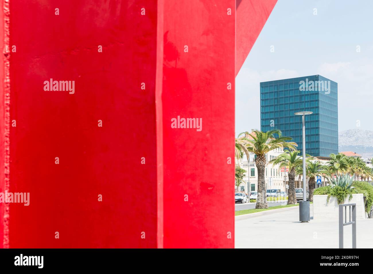 Red sculpture of visual artist Jagoda Buic and glass cube of Hotel Marjan in the background on the boulevard of the ACI Marina in Split, Croatia Stock Photo
