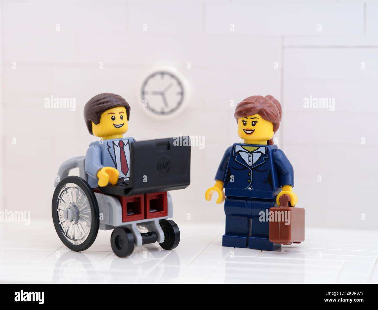 Tambov, Russian Federation - September 6, 2022 A Lego businessman minifigure in a wheelchair using a laptop with a lego businesswoman minifigure stand Stock Photo