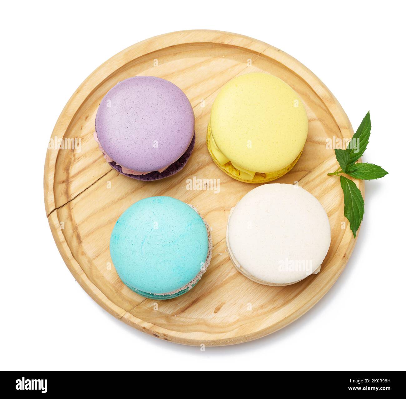 Round macaroons with different flavors on a wooden plate, top view ...