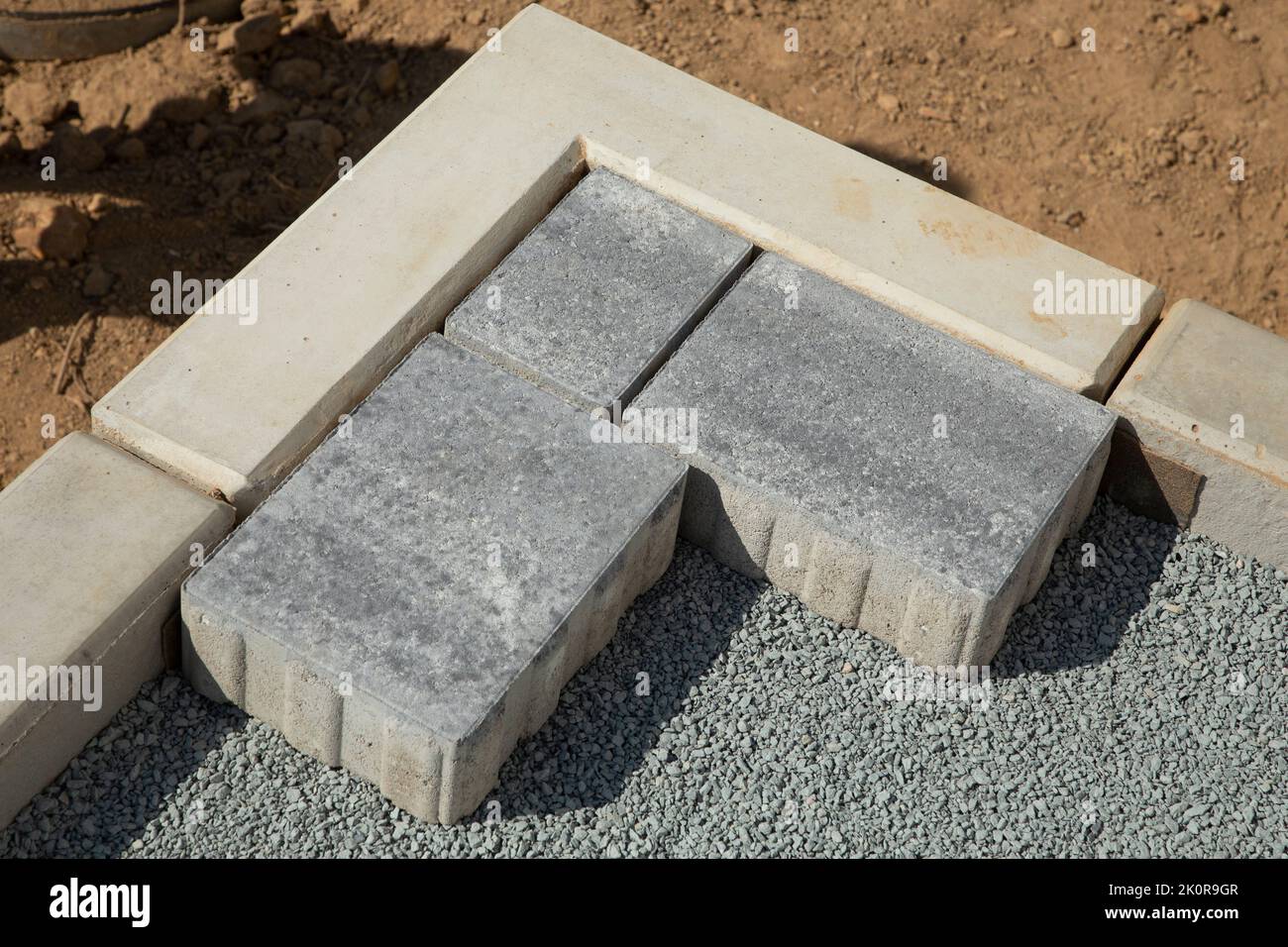 Laying gray concrete paving slabs in the courtyard of the house on a sandy foundation. Stock Photo