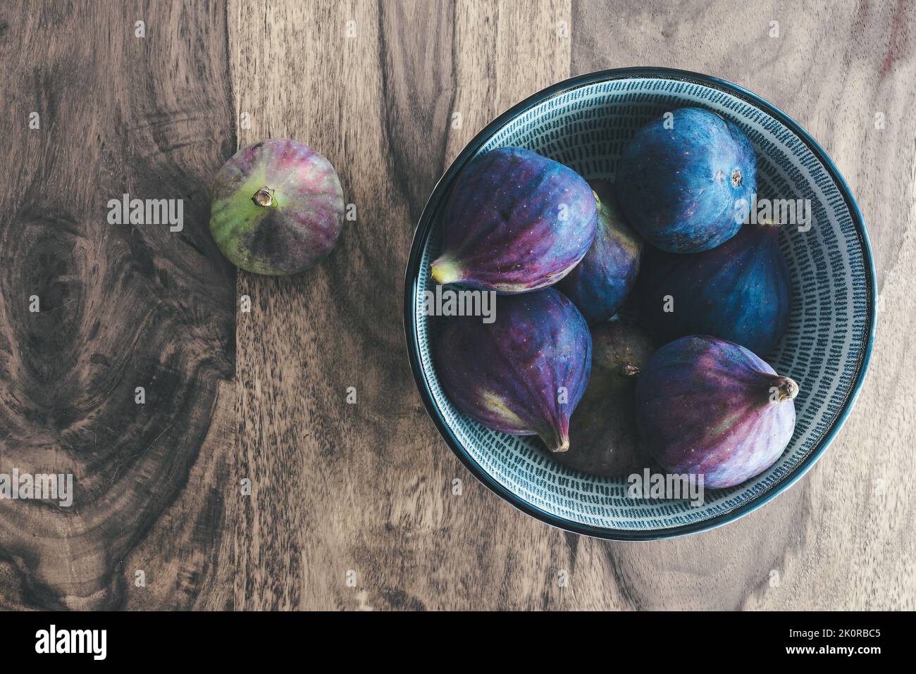 top down view of fresh figs in bowl on wooden table. Stock Photo