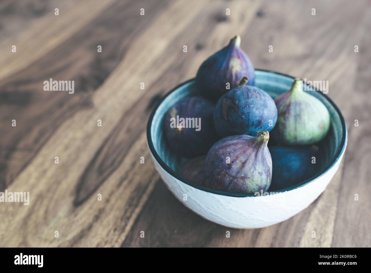 high angle view of fresh figs in bowl on wooden table Stock Photo