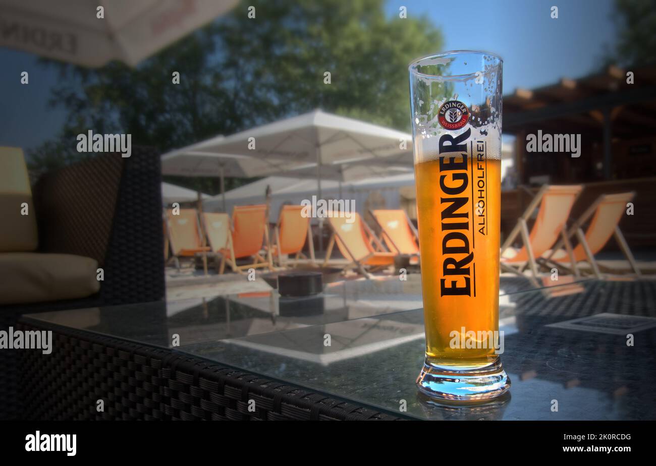 Erdinger wheat beer without alcohol in a half-full glass on a table in front of a blurred beach bar backdrop in Gifhorn, Germany, September 6, 2022 Stock Photo