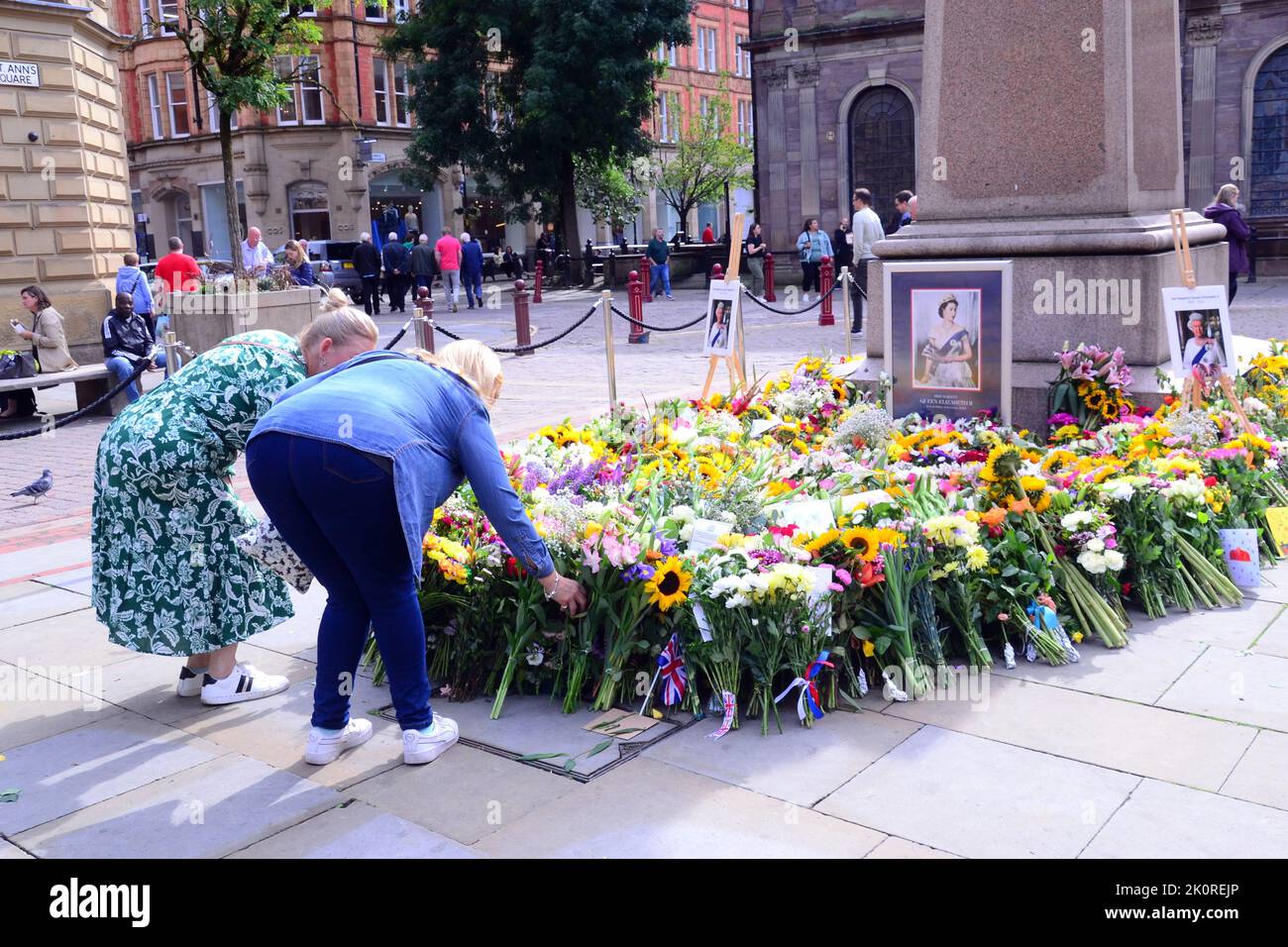 Manchester, UK, 13th September, 2022.  Women leave flowers in St Ann's Square, Manchester, United Kingdom, as a tribute to Her Majesty, Queen Elizabeth II. The Queen died, aged 96, on 8th September, 2022. Manchester City Council has said on its website that the city of Manchester will be observing the official 10-day mourning period and that: 'Residents may wish to lay flowers to mark Her Majesty’s death. You can lay flowers at St Ann's Square'. Credit: Terry Waller/Alamy Live News Stock Photo