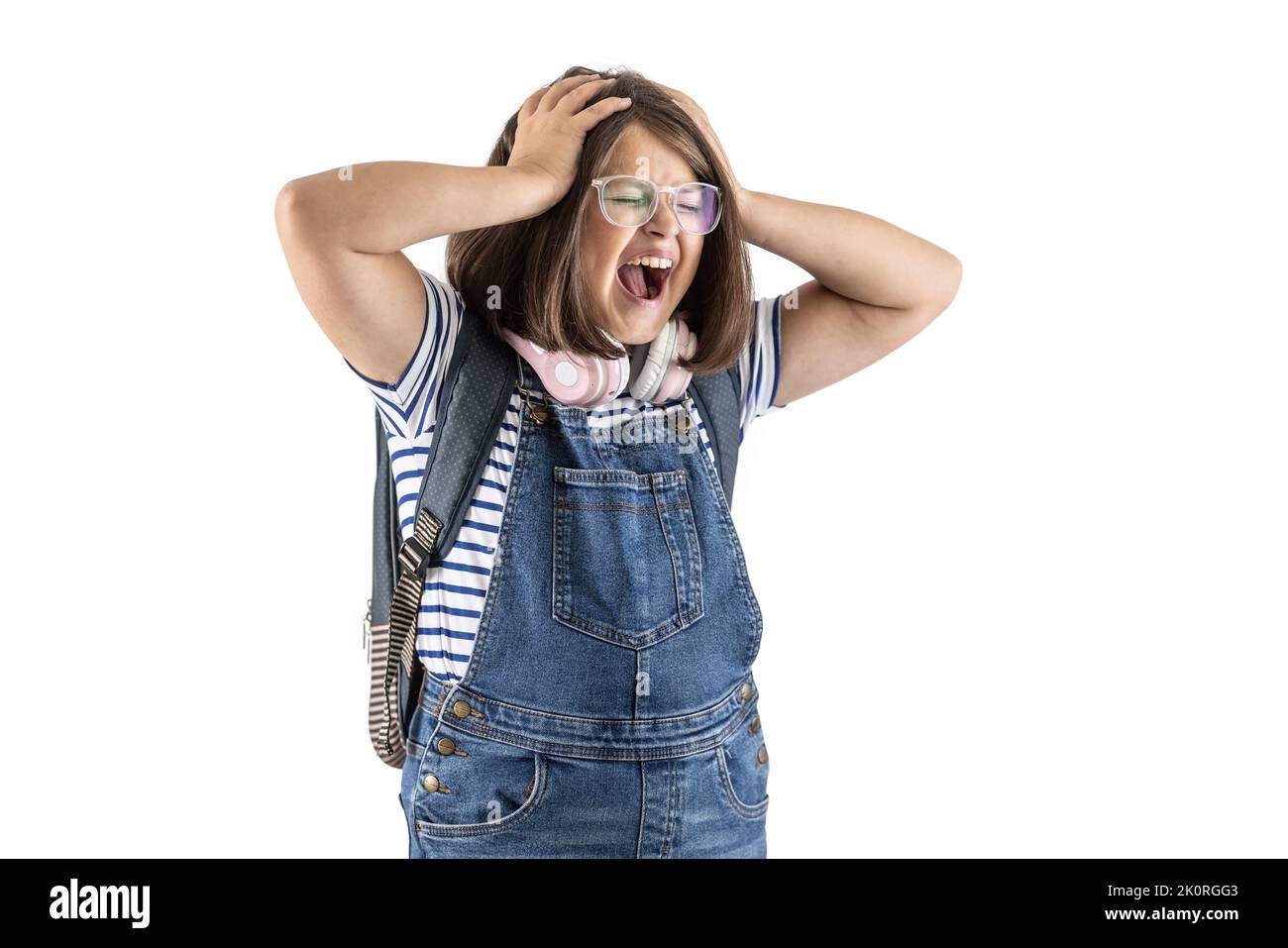 Schoolgirl with backpack and glasses holds her with both hands screaming out loud. Stock Photo