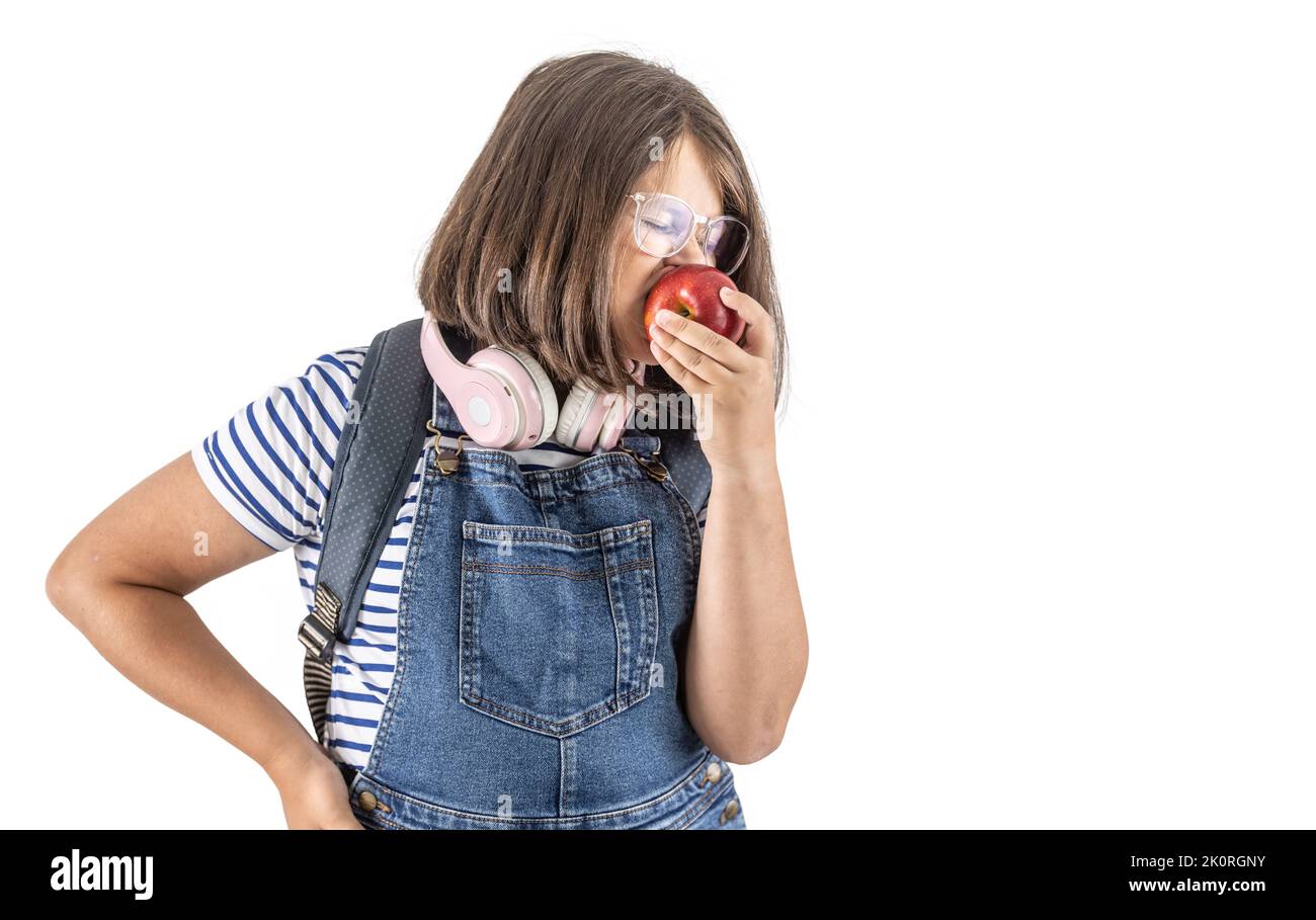 Schoolgirl takes a big bite of a big red juicy apple in her hand. Stock Photo