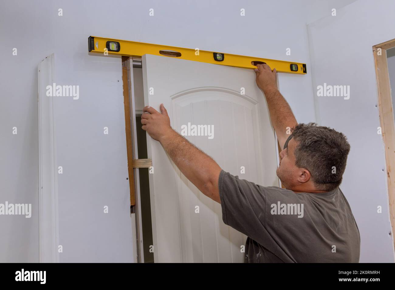 As part of the installation of interior doors in a new house, the employee leveling ensures that the correct door is installed Stock Photo