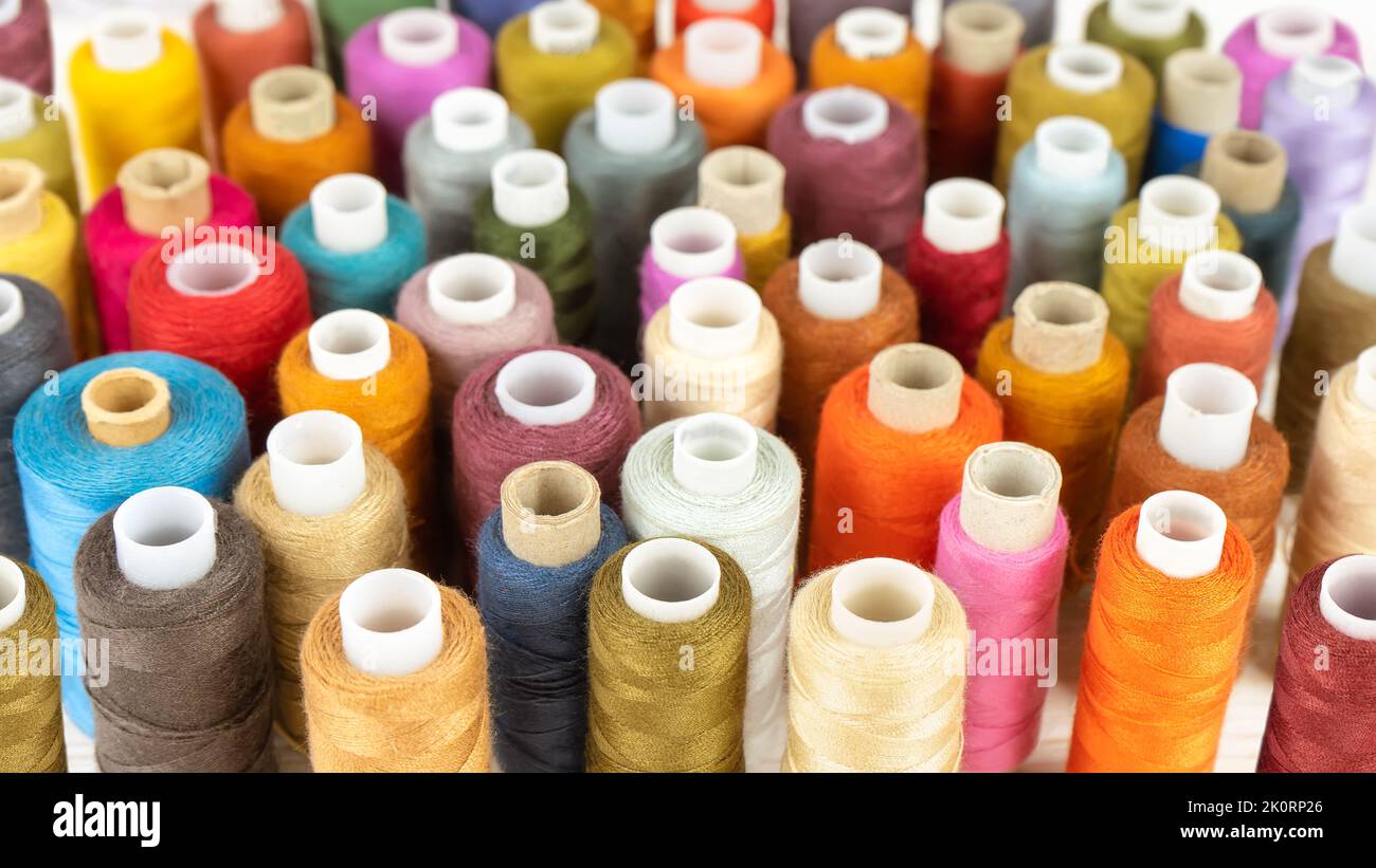 Sewing thread spools multicolored background, scattering of various colors sewing threads, colored yarns Stock Photo