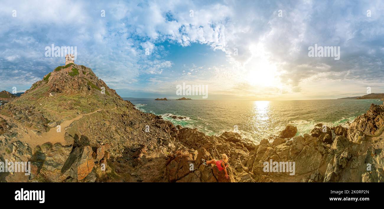 Drone view of a tourist woman sitting on top of Punta Parata by the Sanguinaires islands. Sunset aerial view from Parata tower of Ajaccio town in Stock Photo