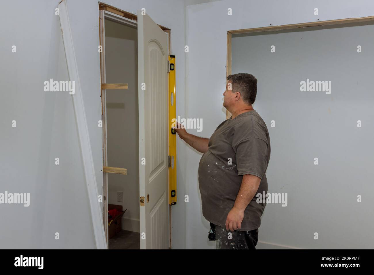 Worker levels the interior doors in a new house as they are being installed, the contractor checks that the door is being installed correctly Stock Photo