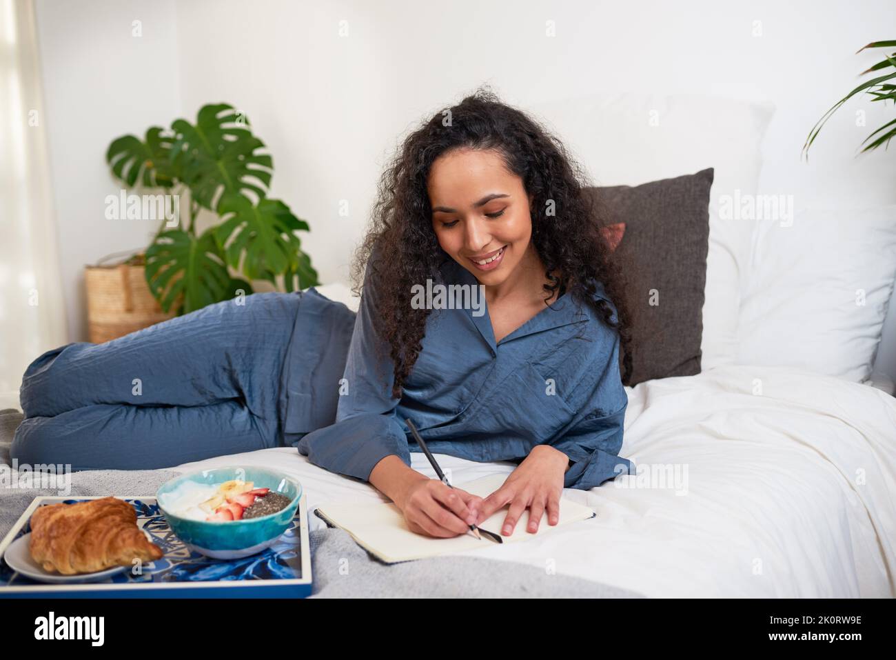 A young woman has a selfcare day in bed eating breakfast and