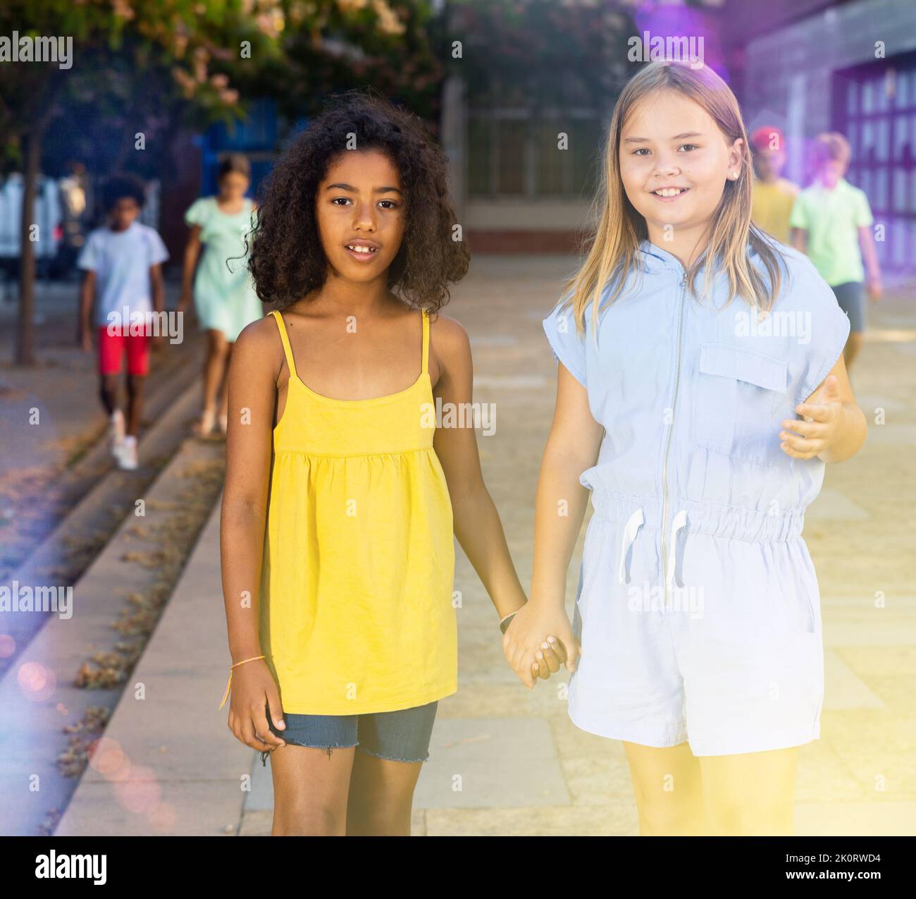 Two young girls walking through city streets together Stock Photo - Alamy