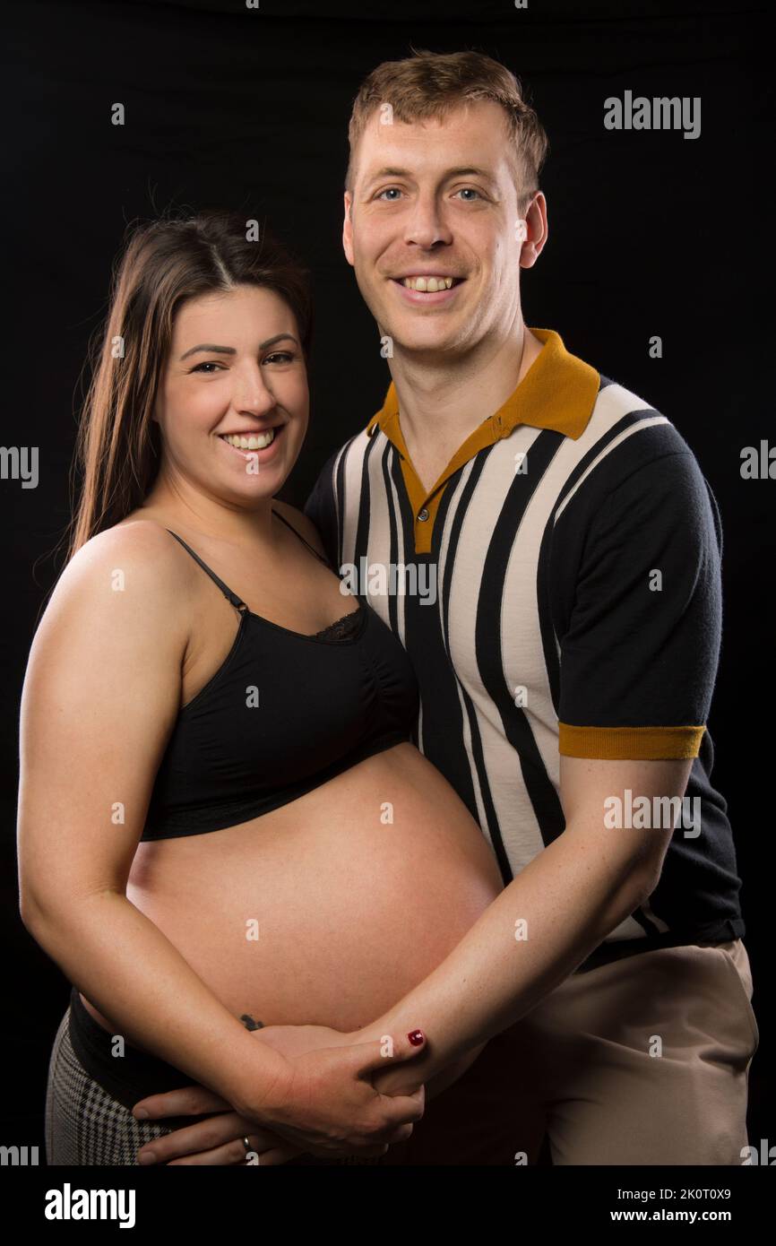Mother and father to-be embrace each other and the baby bump. Stock Photo