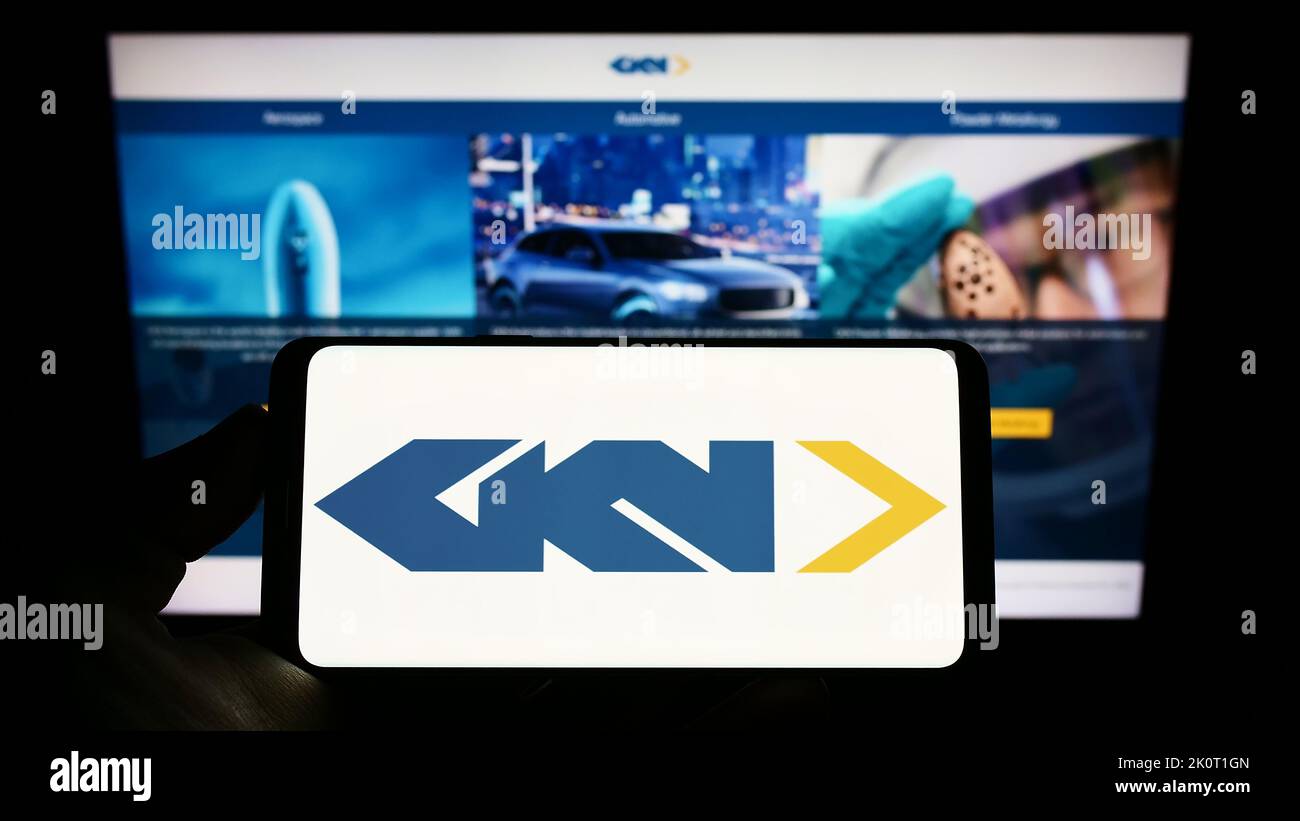 Person holding smartphone with logo of aerospace and automotive comopany GKN Ltd. on screen in front of website. Focus on phone display. Stock Photo