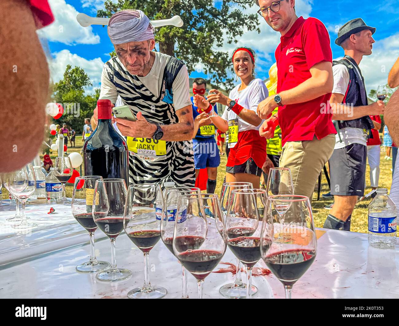 Things are done in style at Chateau Phelan Segur. Here, participants in the 36th Marathon des Chateaux du Medoc are served red wine in glasses. Even on the run one takes the time to capture the labels of the poured Grand Crus Stock Photo