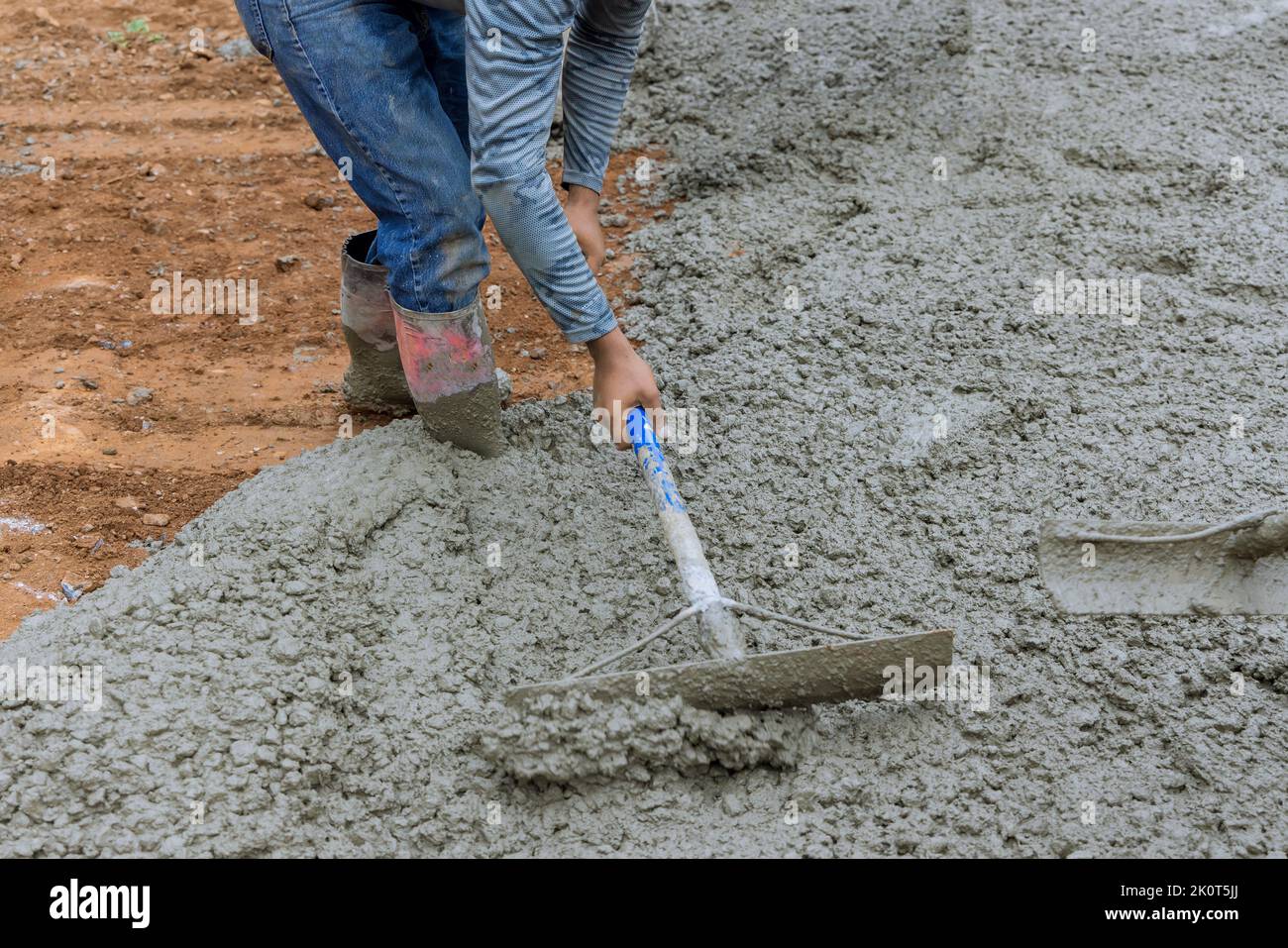 Pouring concrete for a car parking driveway is the work of a worker Stock Photo
