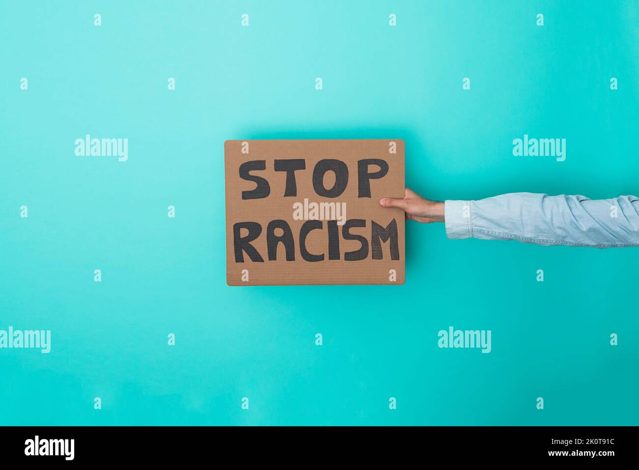 Crop anonymous person showing banner with stop racism text over blue background - Racism and equality concept Stock Photo