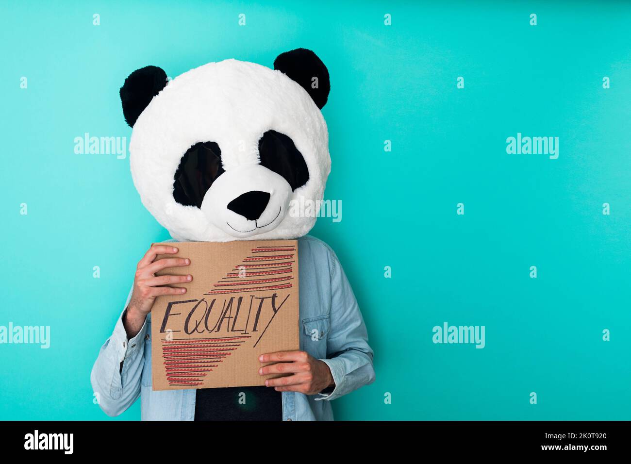 Man wearing panda mask showing cardboard placard with equality text - Racism concept - Copy space Stock Photo