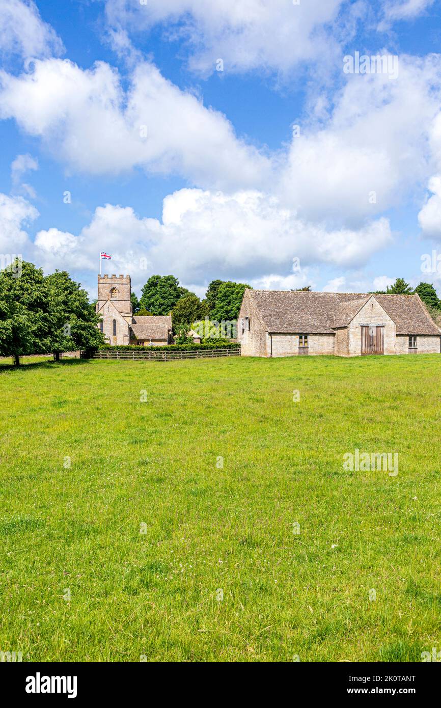 The Norman church of St Michael and All Angels and an 18th century barn in the Cotswold village of Guiting Power, Gloucestershire UK Stock Photo