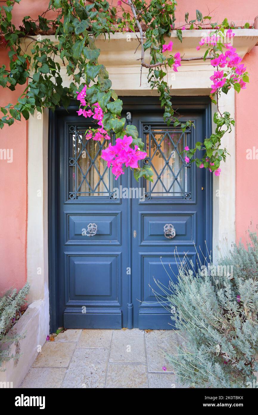 Traditional greek house with flowers in Corfu island, Greece. Blue door surrounded by magenta flowers Stock Photo