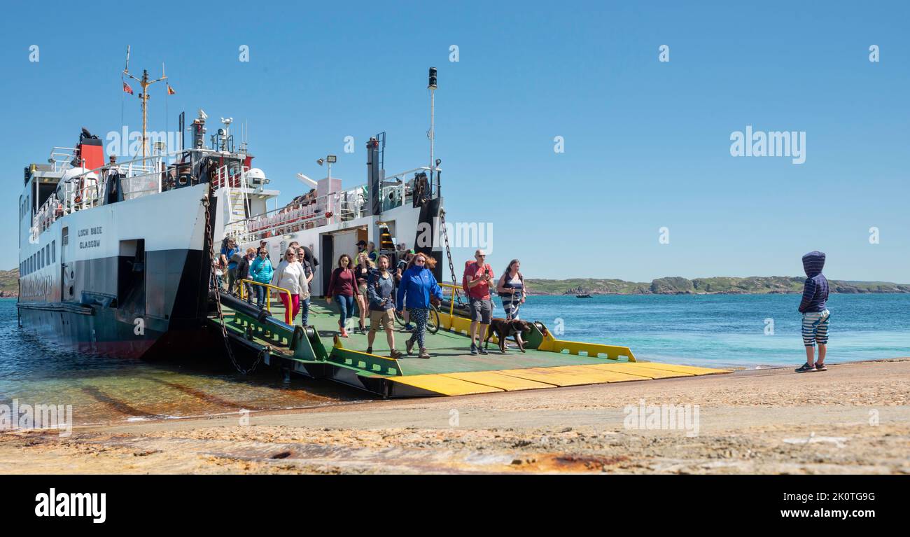 Waiting for Mama:  Young boy in foreground and Passengers disembarking CalMac Ferry between Mull and Iona Scotland Stock Photo