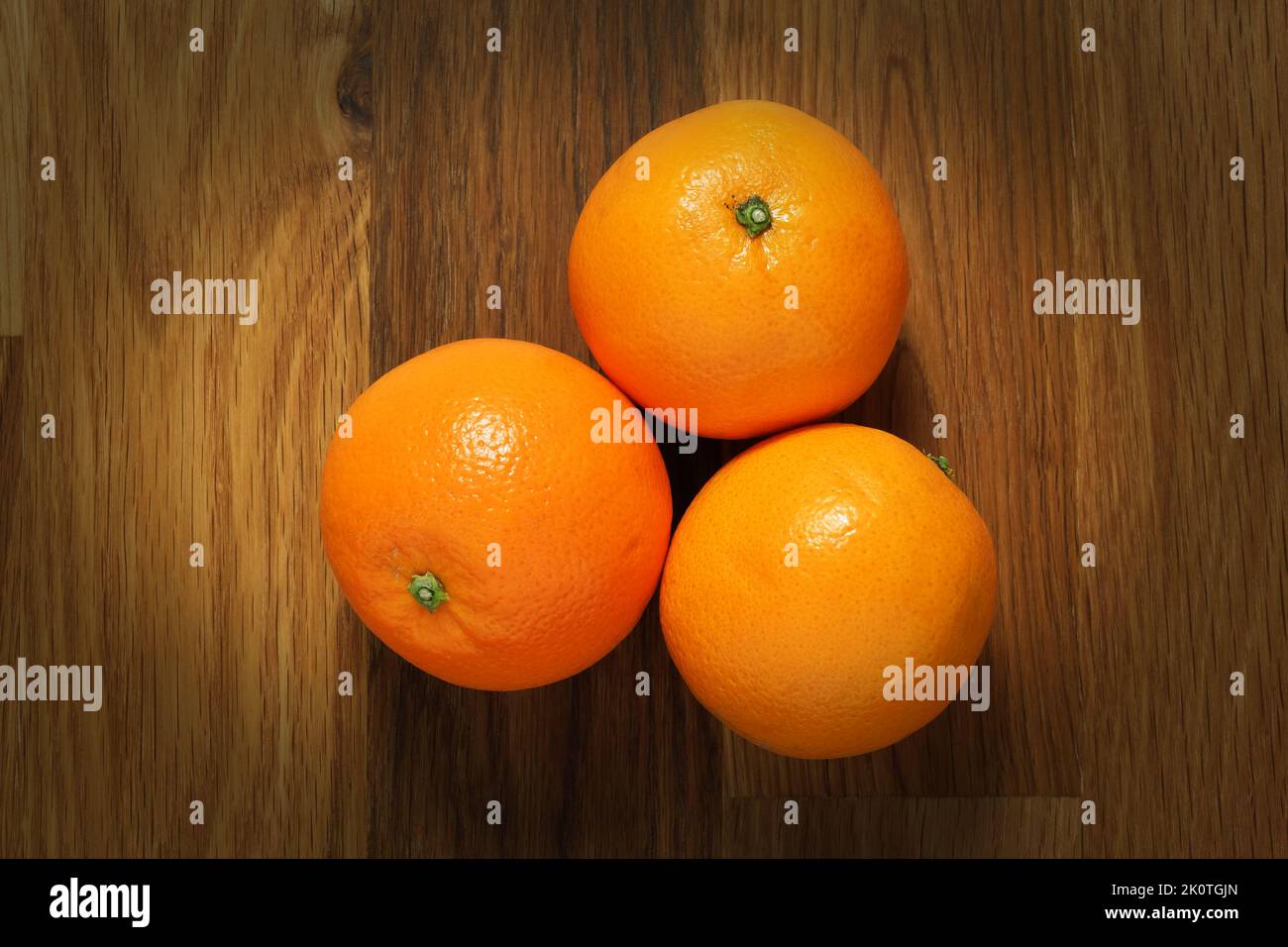 Three oranges shot from above on a wooden table surface Stock Photo