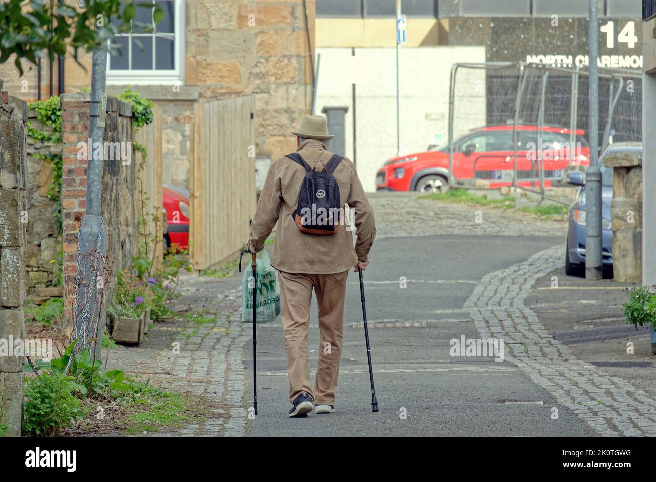 old man with walking sticks west end cobbled street Glasgow, Scotland, UK Stock Photo