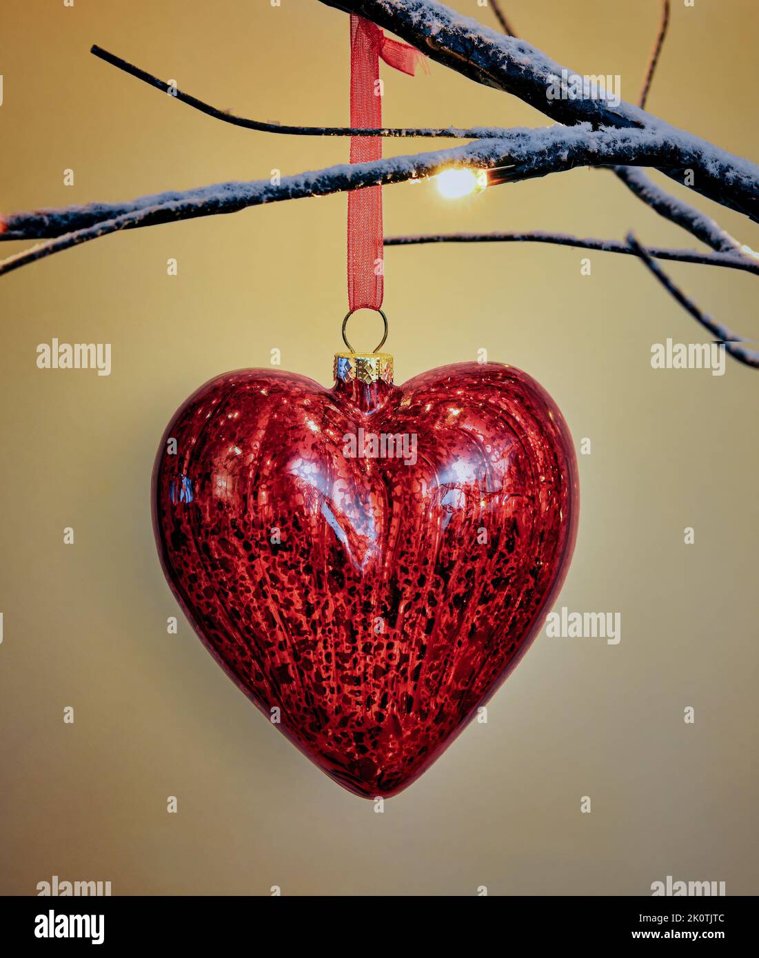 Hanging Christmas Tree Decoration in heart shape in traditional red and gold hanging on Twig tree Stock Photo