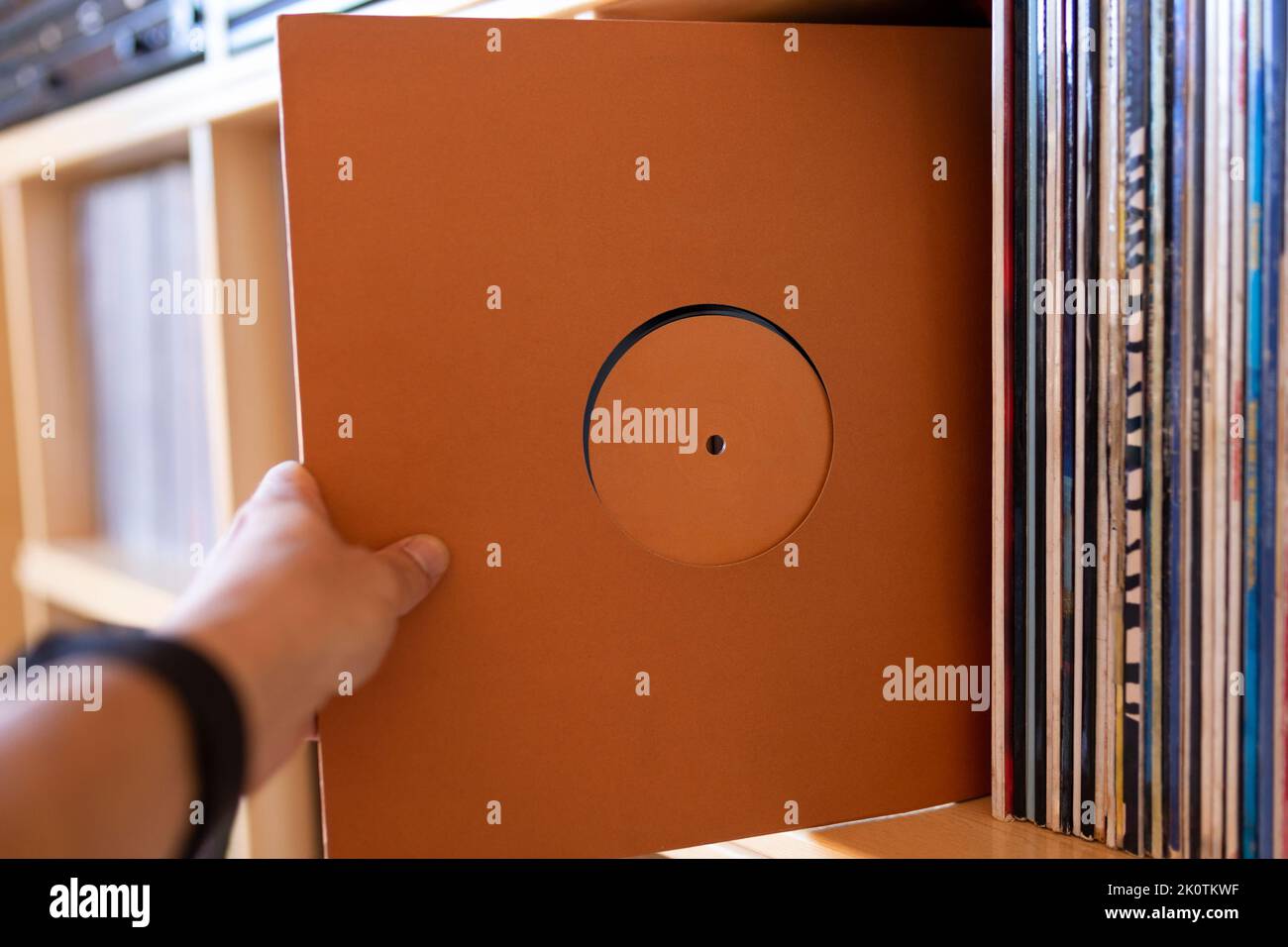 Closeup of person's hand holding a vinyl record from his record library