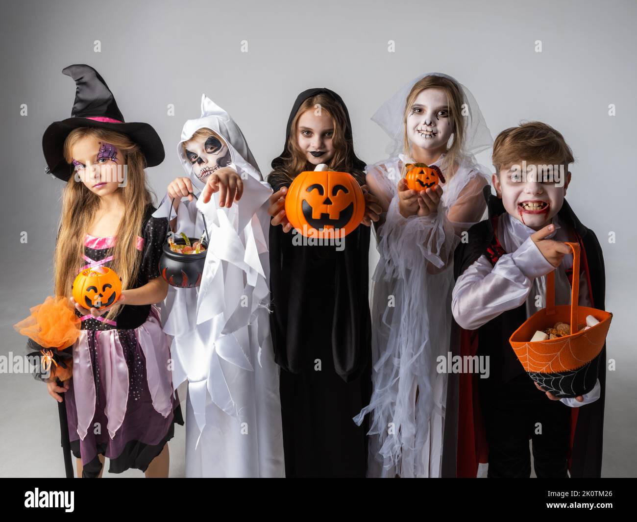Group of children in costumes holding sweets at Halloween party Stock Photo